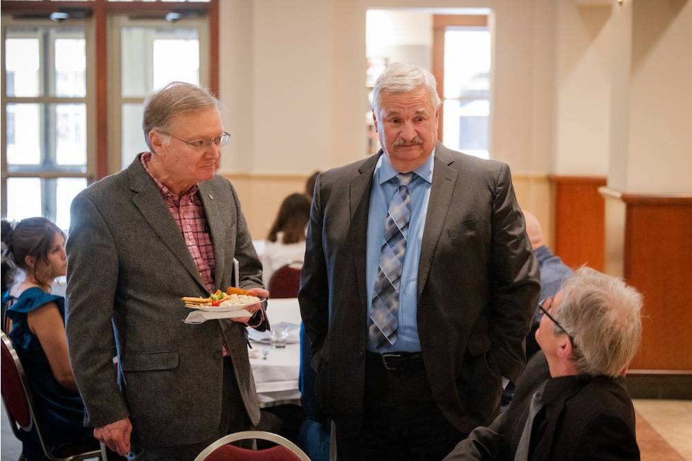 Dean Paul Plotkowski (right) speaking to colleagues.